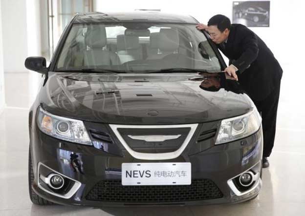 National Electric Vehicle Sweden (NEVS) chairman Jiang Dalong kisses an NEVS electric car as he poses during an interview at its Beijing headquarters building December