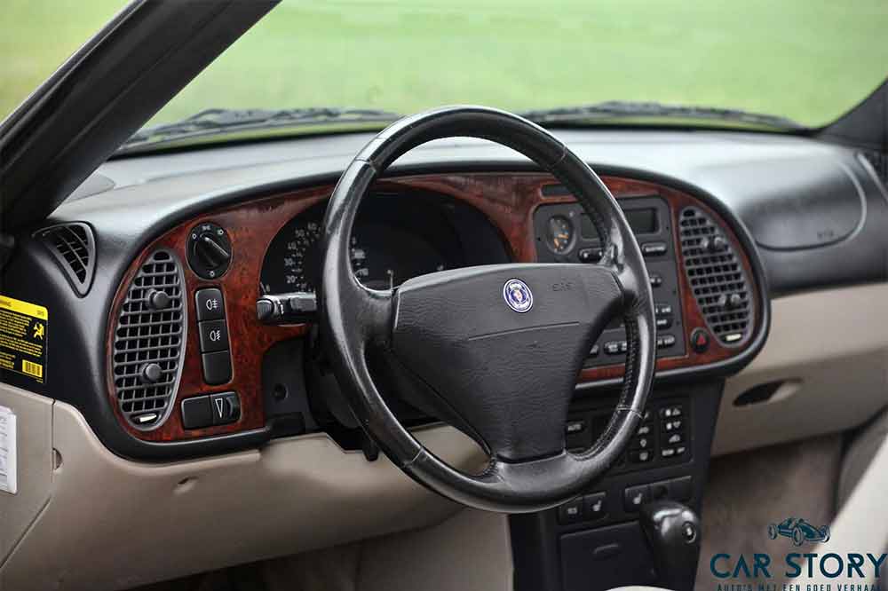 The perfectly preserved interior of the Saab 900NG convertible with real wooden inserts in the dashboard gives the impression of luxury