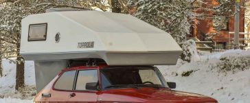 Red Saab 900 fitted with a Toppola camper module parked on a snowy road, highlighting the classic Scandinavian camper setup in winter conditions.