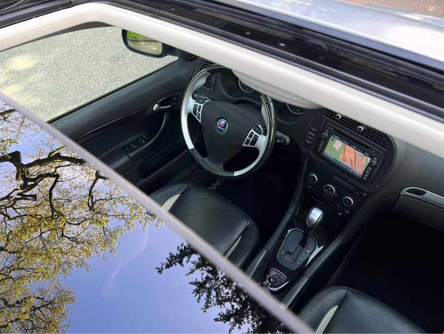 Captured through the open sunroof, a glimpse into the upscale cabin of the Saab 9-3 SportEstate, enhanced with Hirsch Performance upgrades featuring carbon fiber accents and a bespoke leather dashboard, marrying Swedish luxury with sporty elegance