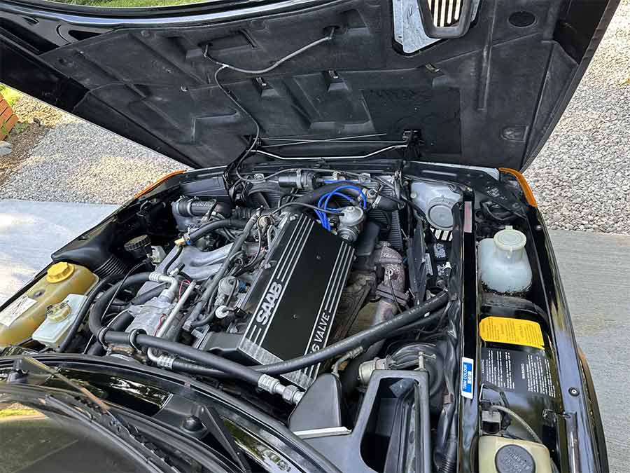 1985 Saab 900 Turbo engine bay with 2.0L 16-valve turbocharged inline-four, featuring original black ribbed Saab valve cover.