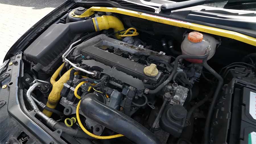 The Quiet Saab 9-3 Aero That Outran Supercars At The Nürburgring 3 Stage 3+ tuned Saab 2.0 Ecotec engine in Shane Conway’s 9-3 Aero, featuring yellow accents, upgraded intake piping, and a clean, dry engine bay.