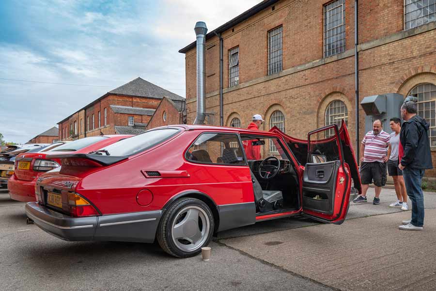 Saab enthusiasts engaging in lively Saab discussions outside Gasoline Juice - where passion and camaraderie meet.