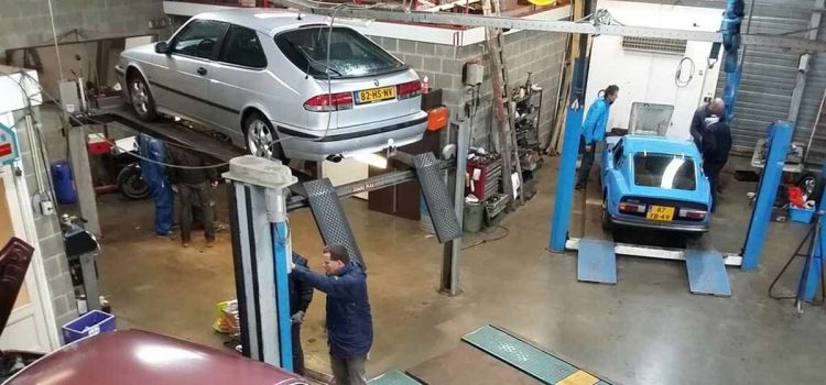 A bustling SAAB enthusiasts' workshop with vintage and modern models being serviced and inspected on lifts, showcasing the vibrant community's dedication to vehicle maintenance and preservation.