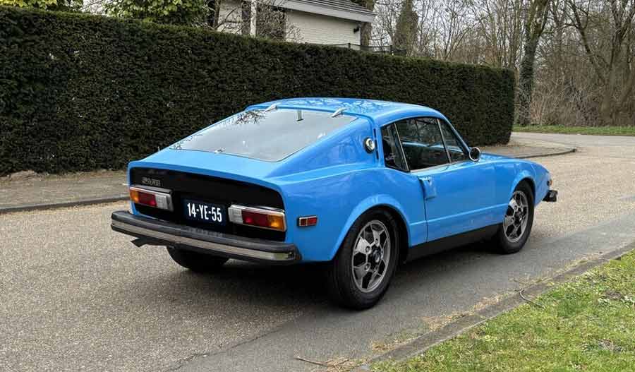 The sleek rear profile of a 1974 Saab Sonett III in True Blue, complete with its distinctively sporty Soccerball wheels and classic black trim.