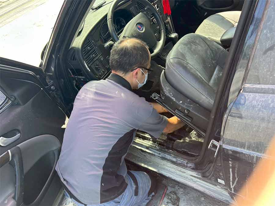 A SAC technician beginning the teardown of the flood-damaged Saab 9-5, removing the interior components after the vehicle arrived from Guangfu.
