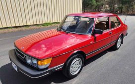 A pristine 1985 SAAB 900S Coupe in its classic cherry red paint, perfectly preserved and reflecting its era's design with sleek lines and distinctive round headlights, stands as a testament to automotive history and timeless appeal.