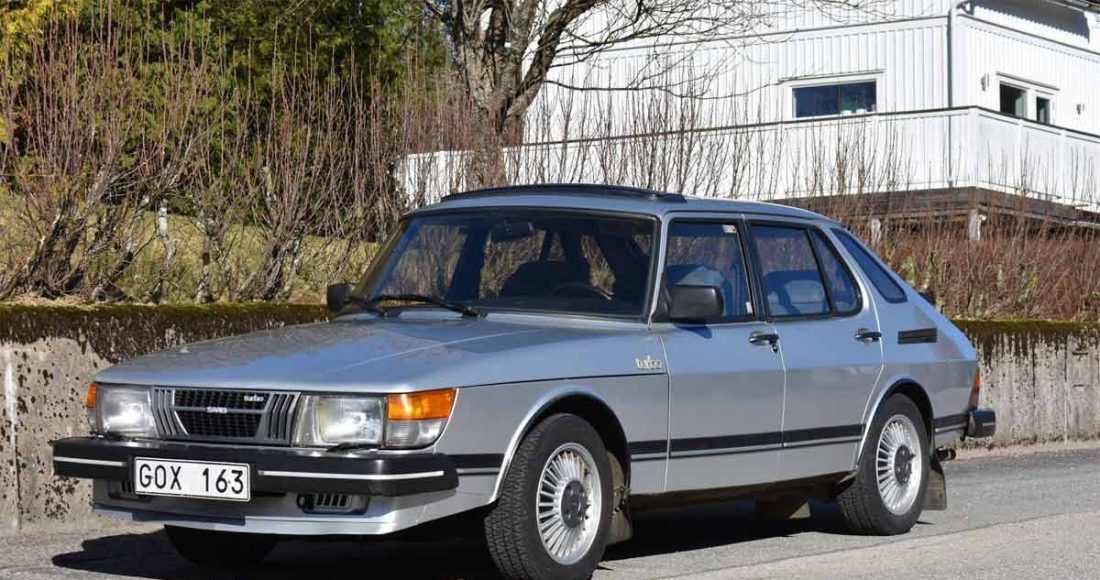 A vintage 1983 Saab 900 Turbo, showcasing its classic four-door body style and distinctive silver paint. The car stands out with its iconic aerodynamic wheel covers and proud Turbo badge, a true representation of the innovative Swedish engineering of the early '80s.