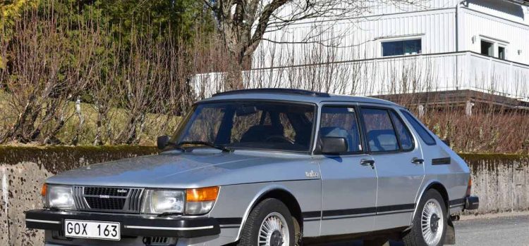 A vintage 1983 Saab 900 Turbo, showcasing its classic four-door body style and distinctive silver paint. The car stands out with its iconic aerodynamic wheel covers and proud Turbo badge, a true representation of the innovative Swedish engineering of the early '80s.