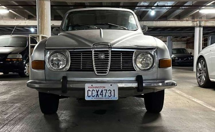 Vintage Charm in Modern Times: The 1972 Saab 96 V4 stands proudly in a contemporary parking garage, its classic features a stark, beautiful contrast to the modern vehicles that flank it."
