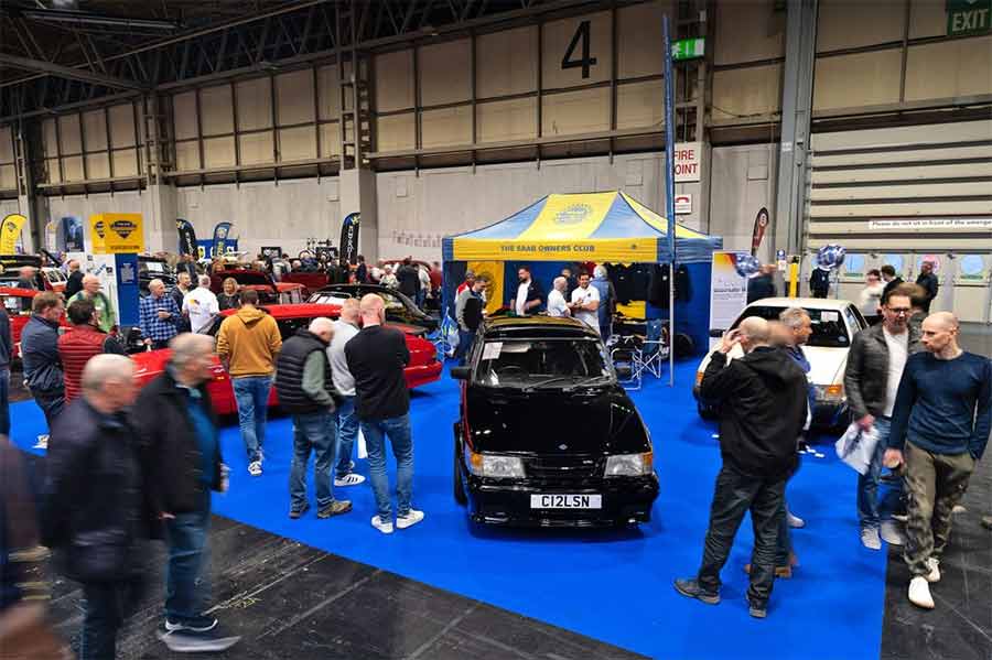 Crowds gathered around the Saab Owners Club of Great Britain stand at NEC Classic Motor Show 2025 featuring Saab 900 Carlsson and 9000 Turbo-16 models