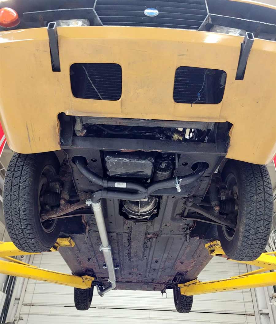 The underside reveals a structurally solid chassis with a newly installed rally-style exhaust system and refreshed brake components — a few signs of surface rust remain, but this Sonett III’s mechanical bones have clearly been brought back to life.